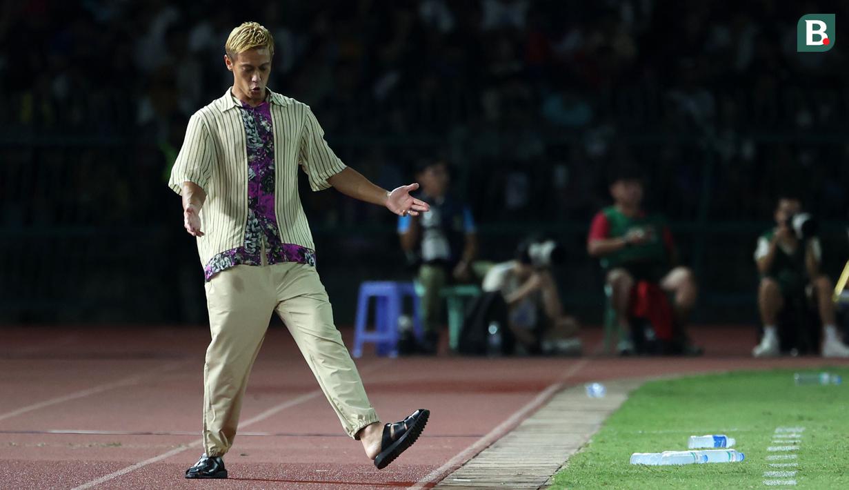 Pelatih Timnas Kamboja U-22, Keisuke Honda memberikan arahan kepada pemainnya saat laga Grup A Sepak Bola SEA Games 2023 melawan Timnas Indonesia di Olympic National Stadium, Phnom Penh, Kamboja, Rabu (10/5/2023) malam WIB. Honda terkenal dengan gaya berpakaian unik saat mendampingi Kamboja pada perhelatan akbar olahraga di Asia Tenggara tersebut. (Bola.com/Abdul Aziz)
