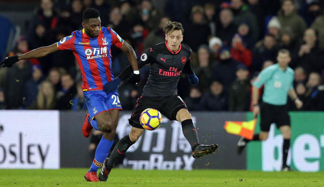 Gelandang Arsenal, Mesut Ozil, berusaha mengahdang bek Crystal Palace, Timothy Fosu-Mensah, pada laga Premier League di Stadion Selhurst Park, Jumat (29/12/2017). Arsenal menang 3-2 atas Crystal Palace. (AP/Alastair Grant)