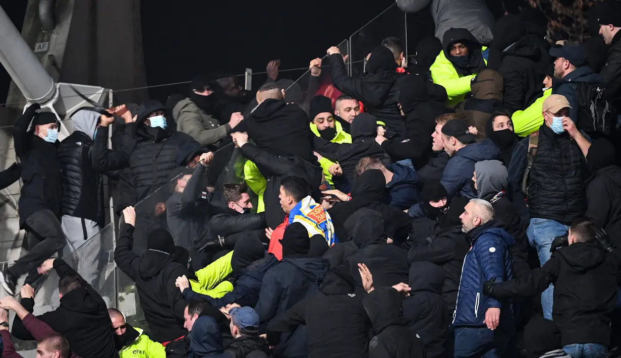 Petugas keamanan turun tangan di tribun penonton ketika para pendukung bentrok pada pertandingan 64 besar Piala Prancis antara Paris FC dan Olympique Lyon di stadion Charlety, Paris,  Jumat (17/12/2021). Laga pun dibatalkan menyusul kerusuhan penonton tersebut. (Bertrand GUAY/AFP)