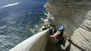 Turis menuruni tangga Raja Aragon di Bonifacio di pulau Corsica, Mediterania Prancis (19/9/2021). Pada kenyataannya, tangga itu digali oleh para biarawan Fransiskan untuk mengakses sumber air minum, yang tidak lagi digunakan. (AFP/Pascal Pochard-Casabianca)