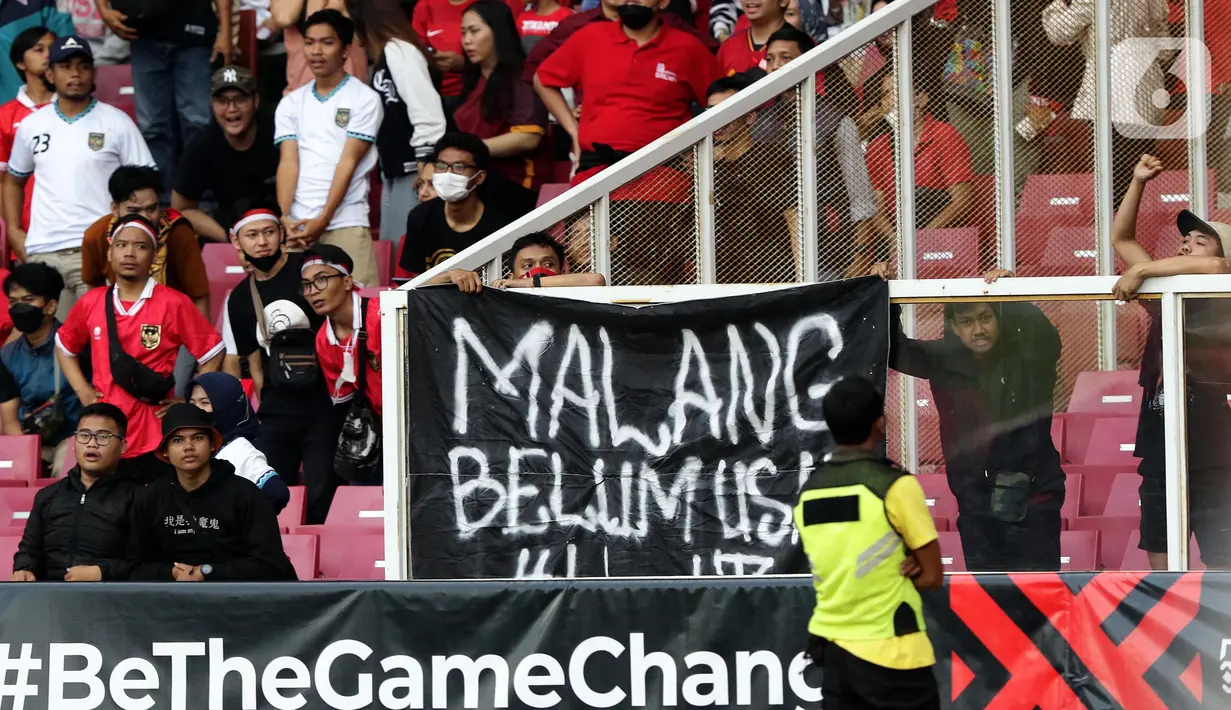 Pendukung timnas Indonesia membentang spanduk bertuliskan “Malang Belum Usai” saat menyaksikan laga kualifikasi Grup A Piala AFF 2022 antara Indonesia melawan Kamboja di di Stadion Utama Gelora Bung Karno, Jakarta, Jumat (23/12/2022). Mereka menyuarakan pengusutan tuntas kasus atas Tragedi Kanjuruhan yang terjadi pada awal Oktober 2022 lalu. (Liputan6.com/Helmi Fithriansyah)