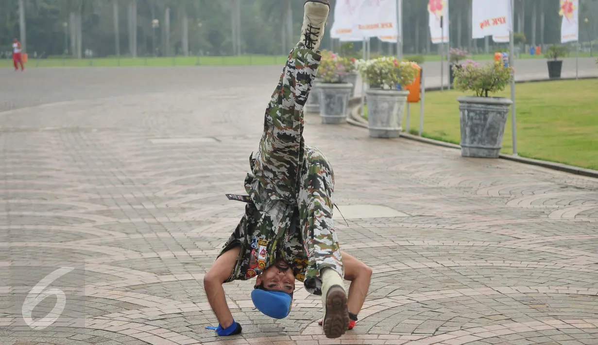 Kopral Bagyo, anggota Polisi Militer Angkatan Darat IV/Surakarta, melakukan aksi jungkir balik mengelilingi tugu Monas, Jakarta, Jumat (17/6). Aksi ini bagian dari kampanye bahaya narkoba dan perayaan ulang tahun ke-70 POM AD (Liputan6.com/Gempur M Surya)