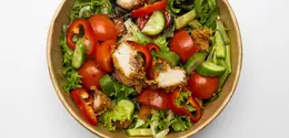 Semangkuk chicken salad yang penuh warna dengan potongan dada ayam panggang dan siraman dressing lemon yang terlihat sangat menggugah selera. [Dok/Freepik.com/kaylabridge].