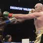 Deontay Wilder (kiri), dan Tyson Fury saling melepaskan pukulan dalam pertarungan tinju kelas berat WBC di Staples Center, Los Angeles, Minggu (2/12/2018) pagi WI. (Foto AP / Mark J. Terrill)