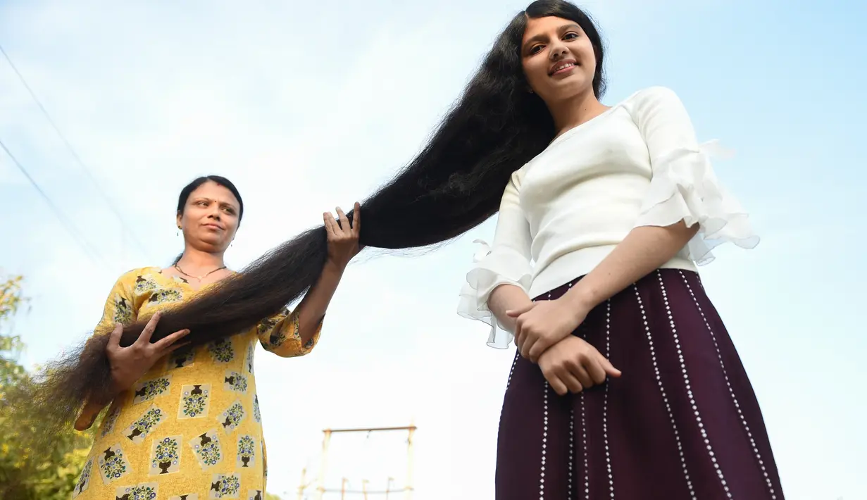 Gadis asal India, Nilanshi Patel (17) berpose dengan ibunya, Kaminibenat di kota Modasa, sekitar 110 Km dari Ahmedabad, Minggu (19/1/2020). Patel mendapat penghargaan Guinness World Record sebagai remaja yang punya rambut terpanjang di dunia dengan panjang hingga 190 cm. (SAM PANTHAKY/AFP)