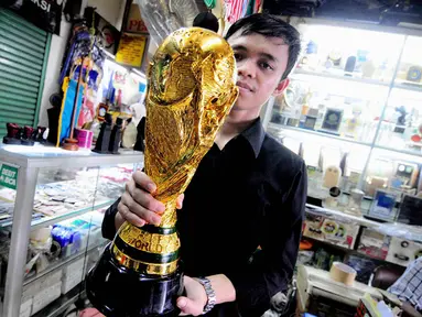 Seorang pedagang menunjukkan replika Piala Dunia di sebuah toko kawasan Pasar Senen, Jakarta, Selasa (24/6/14). (Liputan6.com/Faizal Fanani)