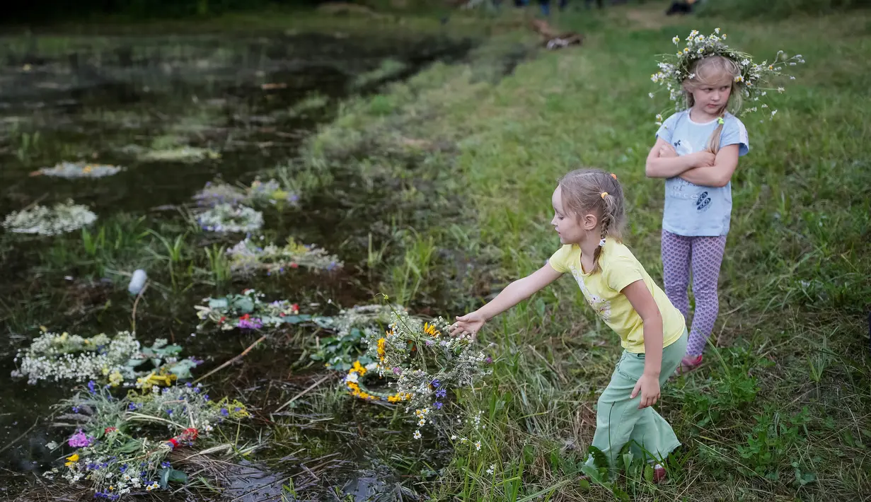  Seorang bocah melempar mahkota bunga ke sungai saat perayaan Ivan Kupala di Kiev, Ukraina, Rabu (6/7). Mereka percaya akan kembali suci dengan mengikuti perayaan tersebut. (REUTERS/ Gleb Garanich)