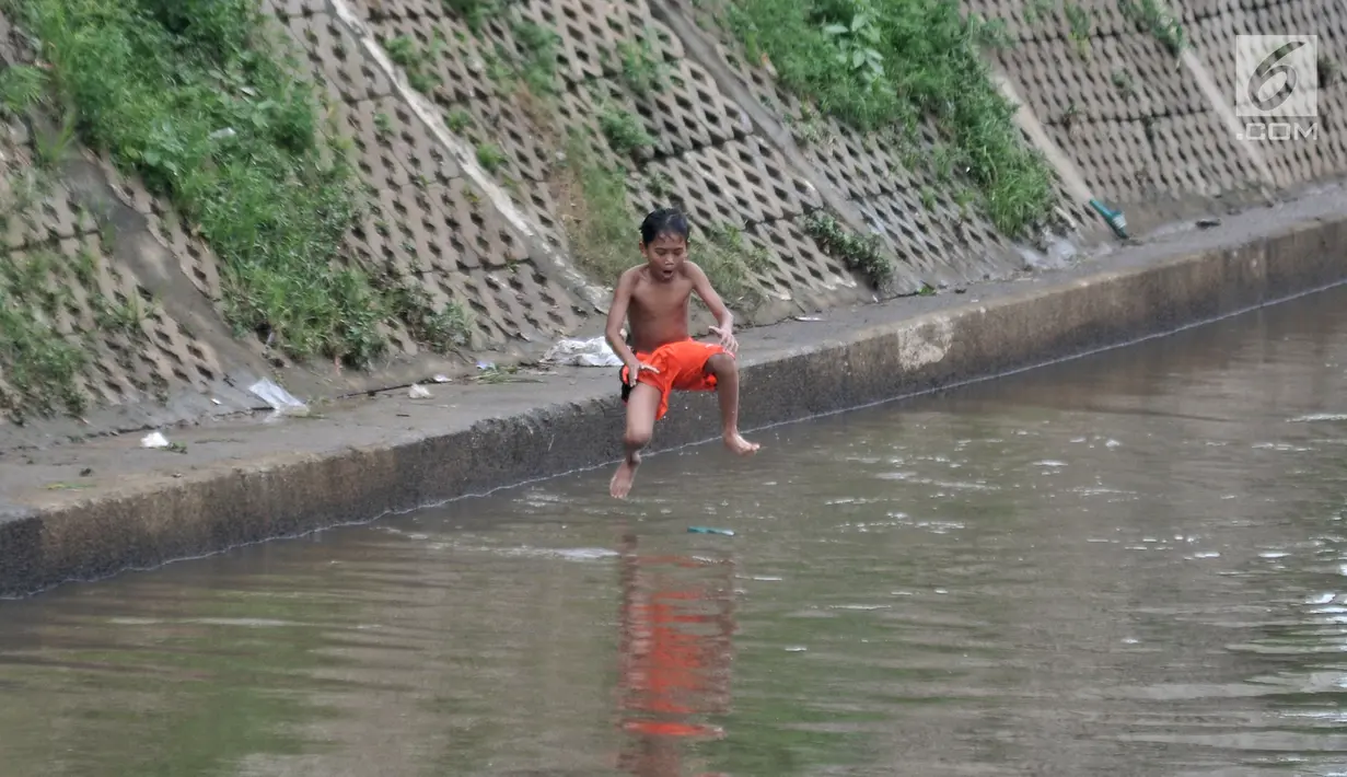 Seorang anak melompat ke Kali Ciliwung, Kampung Pulo, Jakarta, Minggu (27/1). Keterbatasan ekonomi menjadikan Kali Ciliwung sebagai tempat pilihan bagi anak-anak setempat untuk menghabiskan waktu bermain saat libur sekolah. (Merdeka.com/Iqbal Nugroho)