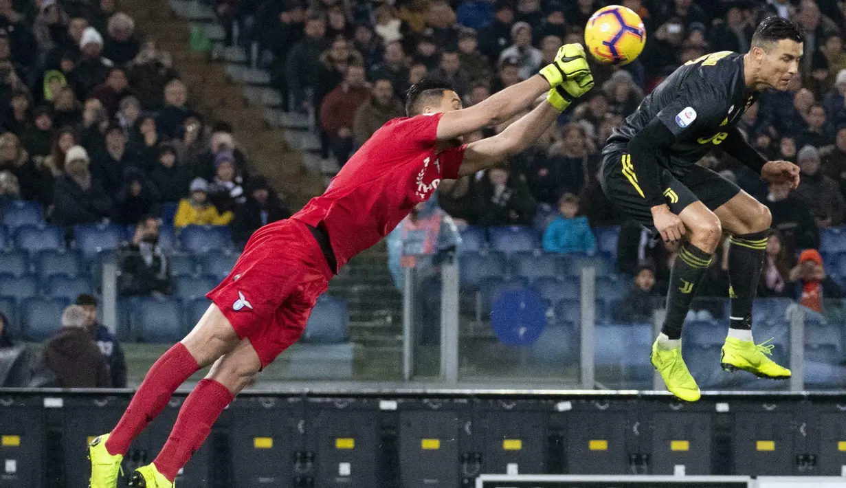 Striker Juventus, Cristiano Ronaldo, berebut bola dengan kiper Lazio, Thomas Strakosha, pada laga Serie A di Stadion Olympic, Minggu (27/1). Juventus menang 2-1 atas Lazio. (AP/Claudio Peri)