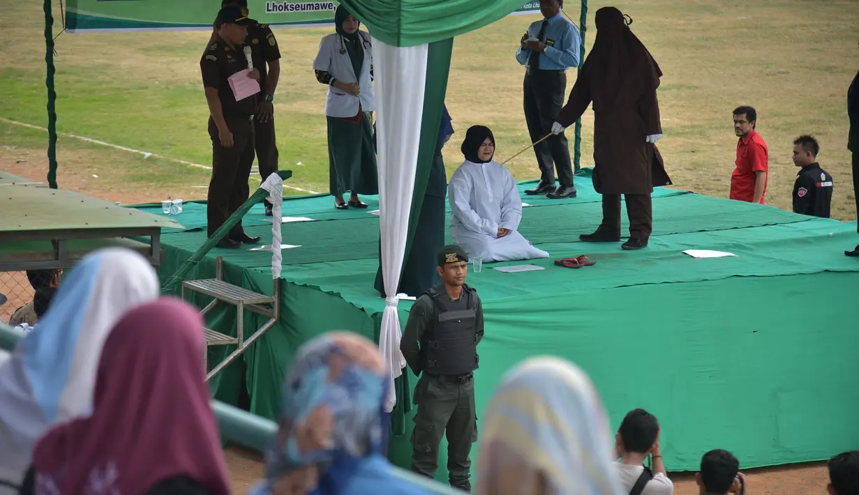 Seorang wanita dicambuk setelah ketahuan melakukan hubungan seks pranikah di sebuah stadion di Lhokseumawe di provinsi Aceh (31/7/2019). Dua pria dan seorang wanita dicambuk secara terbuka sebanyak 100 kali karena melanggar hukum Islam di daerah tersebut. (AFP Photo/Rahmad Mirza)