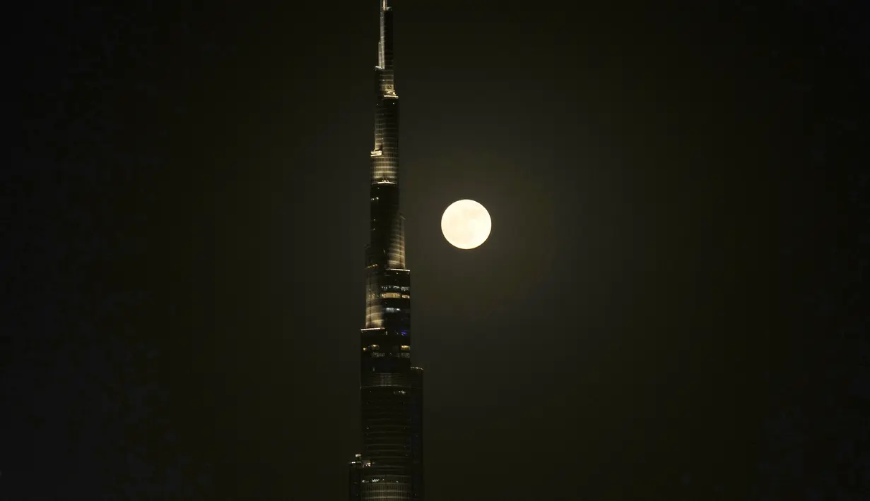 Supermoon terbit di belakang Burj Khalifa, menara tertinggi dunia di Dubai, Uni Emirat Arab, Senin (3/7/2023). Buck Moon digambarkan sebagai supermoon karena akan sedikit lebih dekat ke Bumi, sehingga akan terlihat sedikit lebih besar dan lebih terang.(AP Photo/Kamran Jebreili)