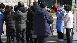 Pekerja medis menggunakan pengeras suara saat orang-orang menunggu tes virus corona di tempat pengujian darurat di Seoul, Rabu (23/2/2022). Kasus harian COVID-19 baru Korea Selatan mencapai rekor tertinggi, melonjak menjadi 171.452 dari 99.569 kasus sehari sebelumnya. (AP Photo/Ahn Young-joon)