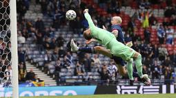 Kiper Republik Ceko, Tomas Vaclik berusaha menepis bola dari sundulan pemain Skotlandia, Lyndon Dykes pada pertandingan grup D Euro 2020 di stadion Hampden Park, Glasgow, Senin (14/6/2021). Dengan kemenangan ini, Ceko menggeser Inggris dari puncak klasemen sementara. (Stu Forster, Pool via AP)