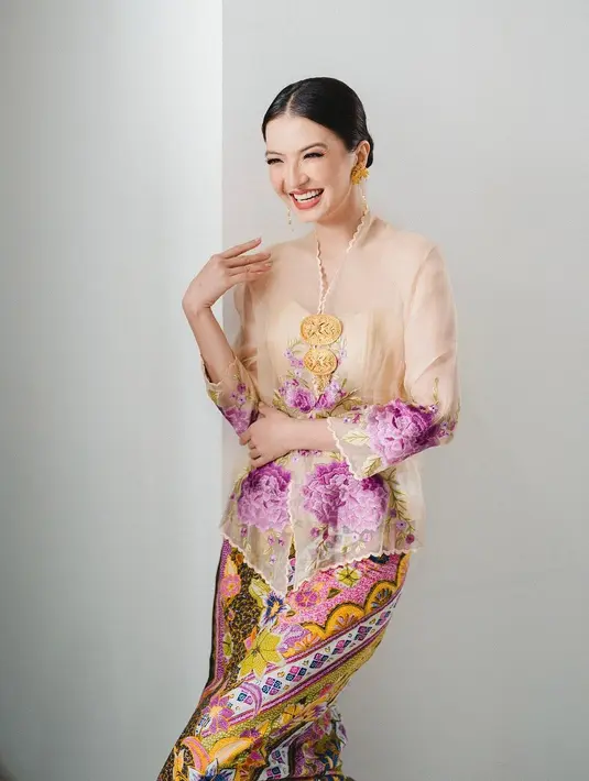Raline Shah mengenakan kebaya encim berwarna cream dengan bordiran bunga ungu dipadukan dengan kain batik nuansa kuning-ungu. [Instagram/ralineshah]