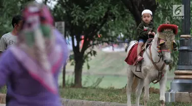 Seorang anak menunggangi kuda di kawasan Kanal Banjir Timur, Jakarta, Selasa (5/6). Berkuda mengelilingi kawasan Kanal Banjir Timur menjadi salah satu pilihan warga untuk ngabuburit sembari mengajak anak-anak bermain. (Merdeka.com/Iqbal S. Nugroho)
