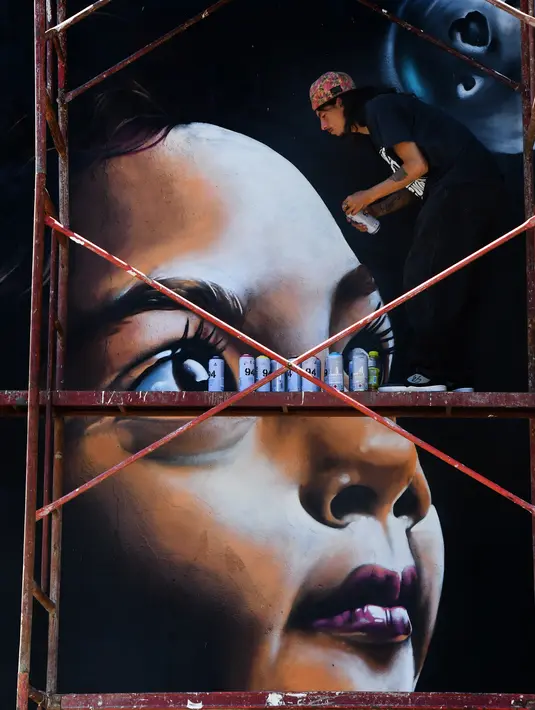 Seorang seniman membuat mural potre anak saat Festival Aliados di San Jose, Costa Rica (11/3). Acara festival seni ini dimeriahkan oleh 50 seniman dari 10 negara. (AFP Photo/Ezequiel Becerra)