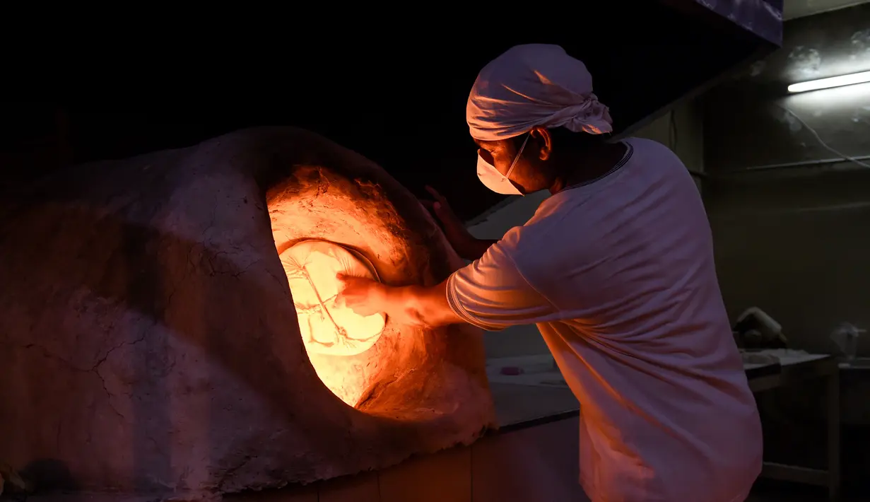 Pedagang India mengenakan masker menyiapkan roti selama bulan suci Ramadan di Bilad al-Qadeem, pinggiran ibukota Bahrain, Manama, di tengah pandemi COVID-19 yang sedang berlangsung (10/5/2020). (AFP/Mazen Mahdi)