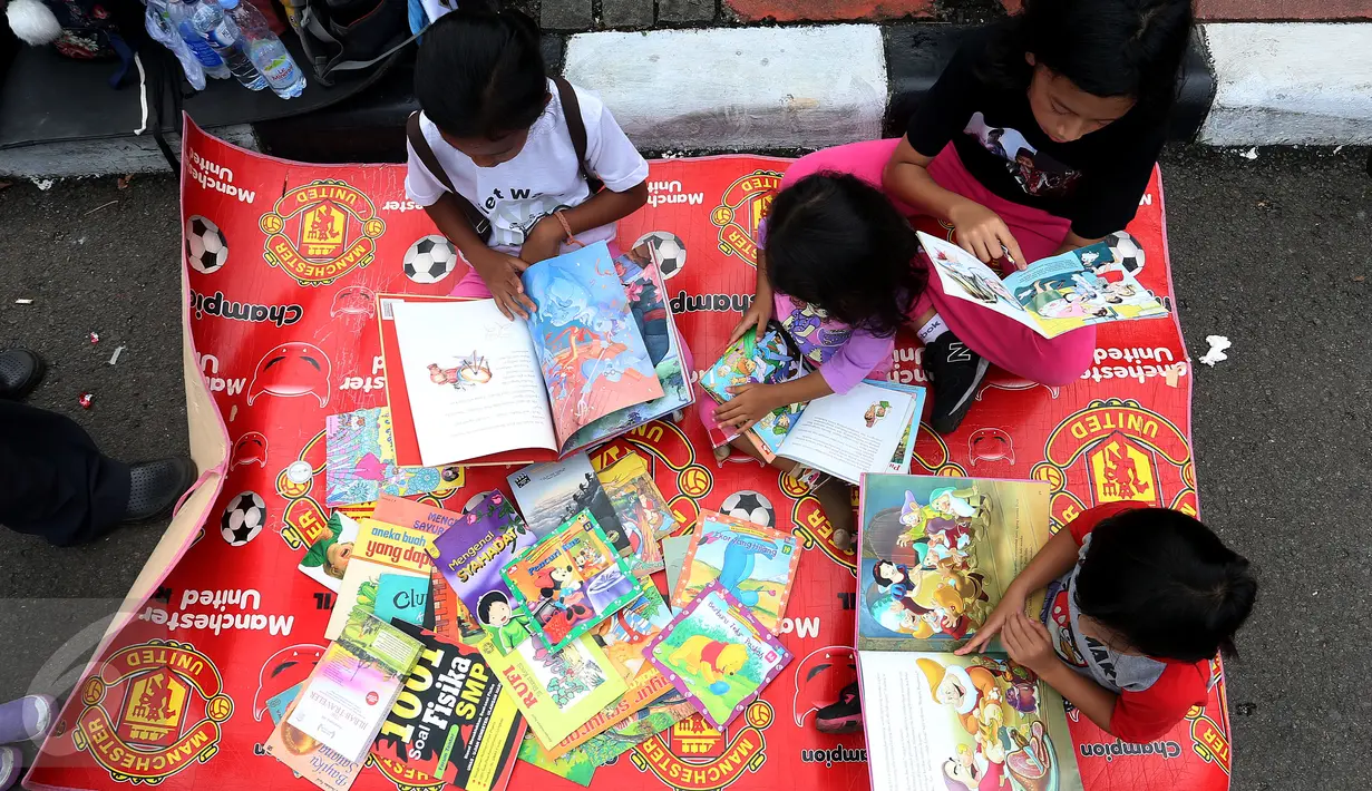 Sejumlah anak membaca buku di Kawasan Bundaran HI saat berlangsungnya Hari Bebas Kendaraan Bermotor atau Car Free Day (CFD), Jakarta, Minggu (2/4). Gerakan yang digagas oleh komunitas "Buku 100 Desa" . (Liputan6.com/Johan Tallo)