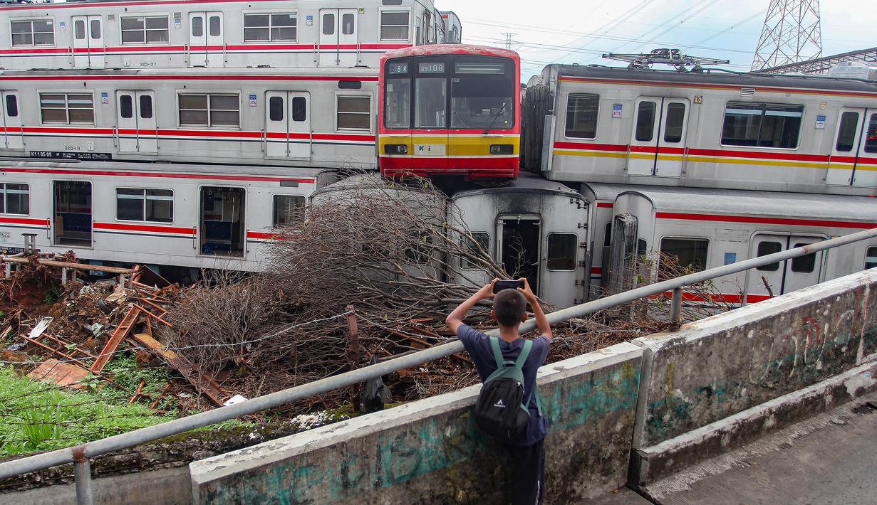 Seorang anak mengabadikan tumpukan Kereta Rel Listrik (KRL) afkir di Depo Depok, Jalan Kampung Rawageni, Cipayung, Kota Depok, Jawa Barat, Selasa (20/01/2026). 242 unit atau gerbong kereta yang sudah tidak terpakai dan ditumpuk di Depo Depok, Jalan Kampung Rawageni, Cipayung, Kota Depok, Jawa Barat. (Merdeka.com/Arie Basuki)