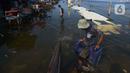 Akivitas warga saat terjadinya banjir rob di Pelabuhan Kali Adem, Muara Angke Jakarta, Rabu (5/1/2022). Menurut BMKG, adanya fase bulan baru yang bersamaan dengan masa Perigee (jarak terdekat bulan bumi) menyebabkan peningkatan signifikan ketinggian pasang air laut. (merdeka.com/Imam Buhori)