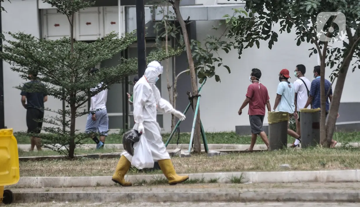 Tenaga kesehatan melintas dekat pasien COVID-19 yang berolahraga di sekitar taman Rumah Sakit Darurat (RSD) Wisma Atlet, Kemayoran, Jakarta, Minggu (6/12/2020). Setiap pagi dan sore hari pihak RSD Wisma Atlet memperbolehkan pasien Covid-19 keluar kamar untuk berolahraga. (merdeka.com/Iqbal Nugroho)
