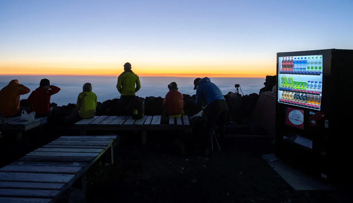 Mesin penjual otomatis dengan minuman hangat dan dingin saat orang-orang menunggu matahari terbit di puncak Gunung Fuji, barat Tokyo pada 19 Juli 2021. Pemandangan matahari terbit di atas lautan awan adalah hadiah indah bagi yang mencapai puncak tertinggi di Jepang. (Charly TRIBALLEAU/AFP)