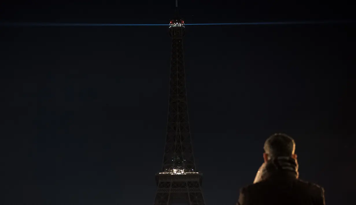 Seorang pria mengambil gambar lampu Menara Eiffel yang dipadamkan sementara di Paris, Rabu (14/12). Lampu Menara Eiffel dimatikan untuk menunjukkan dukungan bagi warga Aleppo di Suriah. (AFP PHOTO/PHILIPPE LOPEZ)