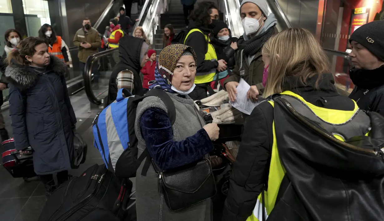 Seseorang berbicara dengan relawan pendukung setelah kedatangan kereta dengan pengungsi Ukraina di stasiun utama di Berlin, Jerman, Selasa (1/3/2022). Diperkirakan 300 orang tiba di Berlin dengan kereta api. Sejumlah relawan kemudian merawat orang-orang yang terdampar. (AP Photo/Michael Sohn)