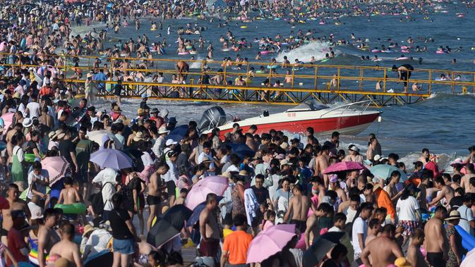 Wisatawan mengunjungi pantai sambil mendinginkan diri di Qingdao, China timur, pada 3 Agustus 2019. Banyak warga di Negeri Tirai Bambu memanfaatkan musim panas dengan mengunjungi pantai untuk mengisi liburan. (Photo by FRED DUFOUR / AFP)