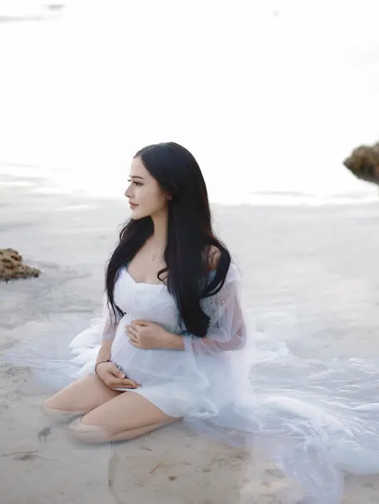 Tanpa didampingi sang suami, Bella Bonita tampil secantik bidadari dalam balutan mini dress putih dengan outer tulle menjuntai panjang sembari memamerkan baby bump-nya. [@bellabonita]