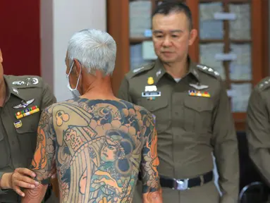 Petugas menunjukkan tato Mantan bos Yakuza asal Jepang, Shigeharu Shirai di sebuah kantor polisi saat konferensi pers di Lopburi, Thailand, Kamis, (11/1). Pria 72 tahun ini ditangkap setelah 14 tahun menjadi buronan. (AP Photo)