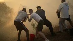 Penduduk setempat menggunakan ember berisi air untuk mencoba memadamkan api yang mendekati rumah mereka di Alcabideche, di luar Lisbon, Portugal, Selasa (25/7/2023). (AP Photo/Armando Franca)