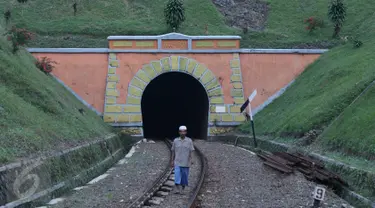 Warga melintas di rel sekitar terowongan Sasaksaat, Bandung Barat, Jawa Barat, Selasa (5/7). Terowongan yang memiliki panjang sekitar 949 meter tersebut menjadi terowongan kereta terpanjang di Indonesia yang masih aktif. (Liputan6.com/Immanuel Antonius)