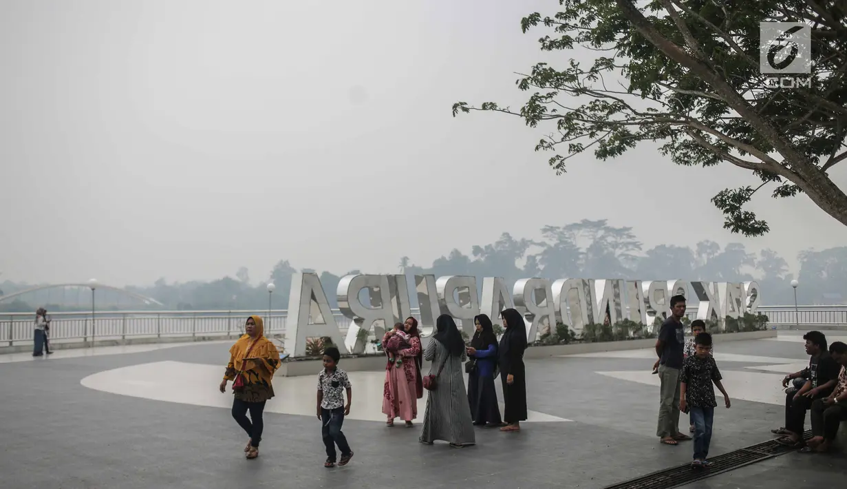 Warga beraktivitas saat asap kebakaran lahan gambut menyelimuti alun-alun Kabupaten Siak, Riau, Kamis (12/9/2019). Asap pekat kebakaran lahan gambut tersebut selain mengganggu kesehatan serta mencemari udara sehingga kualitasnya turun ke status tidak sehat. (Liputan6.com/Faizal Fanani)