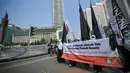 Aktivis Perempuan HTI membawa sebuah spanduk saat melakukan aksi di Bundaran HI, Jakarta, Minggu (22/3/2015). Mereka menolak sistem neoliberalisme dan neoimperialisme yang digunakan oleh Indonesia.(Liputan6.com/Faizal Fanani)