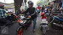 Pengendara motor menuntun kendaraan mereka usai motornya terkena operasi cabut pentil di Jalan Kyai Tapa, Roxy, Jakarta, (23/10/2015). Dengan banyaknya operasi cabut pentil sejumlah juru tambal mandapat tambahan rezeki. (Liputan6.com/Immanuel Antonius)