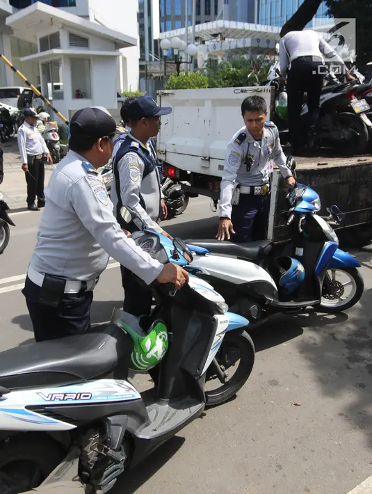 Petugas Dishub DKI Jakarta mengangkut motor saat razia parkir liar di Jalan KH Wahid Hasyim, Jakarta, Rabu (4/4). Dishub DKI Jakarta menertibkan pengendara ojek online yang memarkirkan kendaraan sembarangan di pinggir jalan. (Liputan6.com/Arya Manggala)