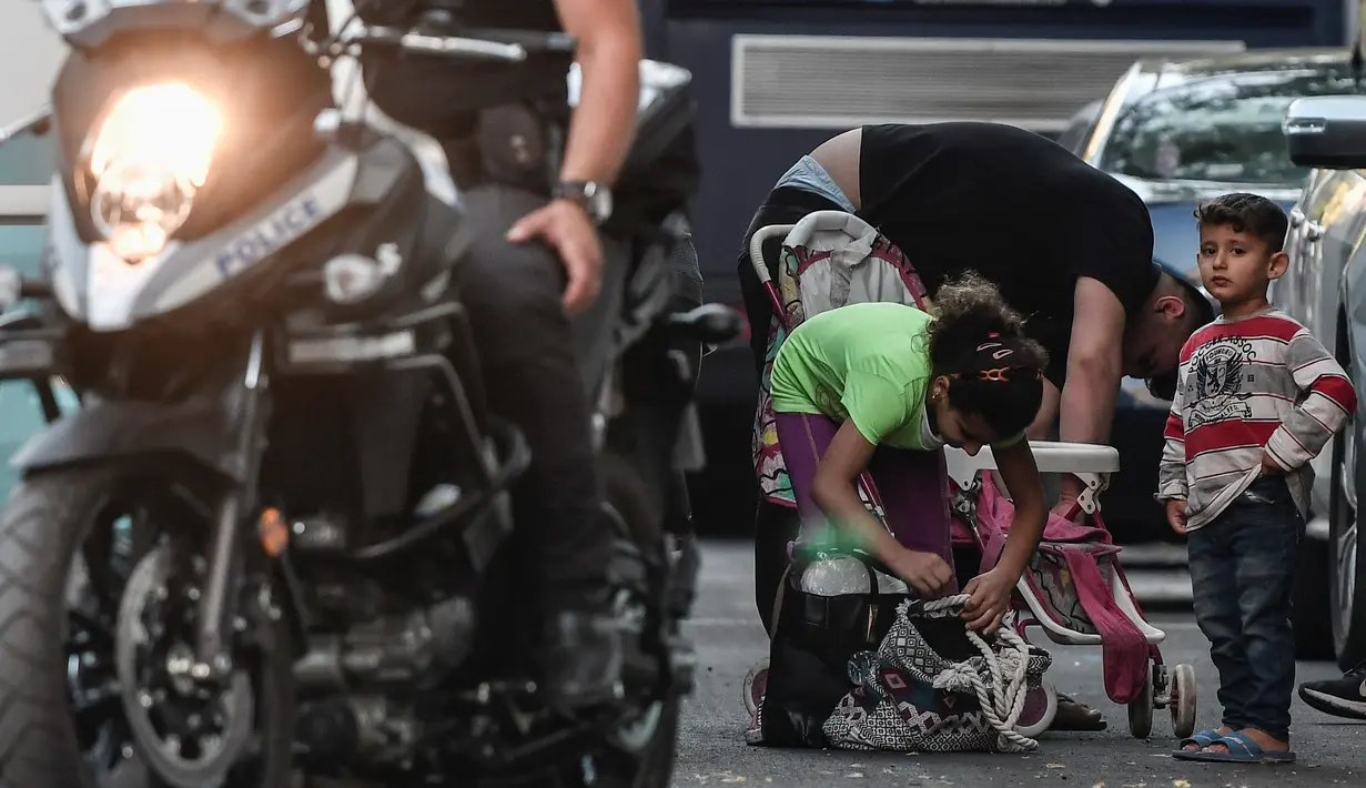 Para migran bersiap naik bus selama operasi polisi di pusat Athena, Yunani (19/9/2019). Polisi di Athena pada 19 September 2019 memindahkan lebih dari 200 migran, termasuk lusinan anak-anak, dari dua tempat di pusat kota sebagai bagian dari pembersihan. (AFP Photo/Louisa Gouliamaki)
