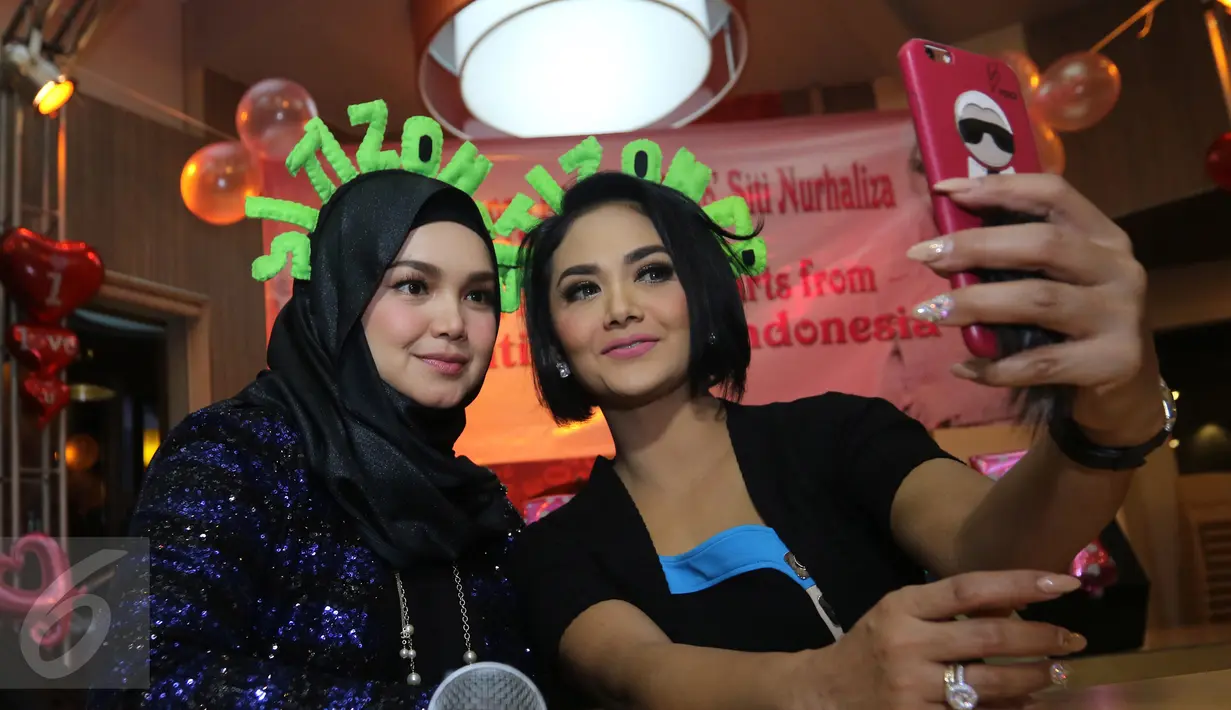 Siti Nurhaliza berfoto bersama Krisdayanti saat merayakan ulang tahun sang Diva asal Malaysia di restoran cepat saji di kawasan Kemang, Jakarta, Minggu (10/1). Pelantun tembang Cindai ini berulang tahun pada 11 Januari. (Liputan6.com/Herman Zakharia)