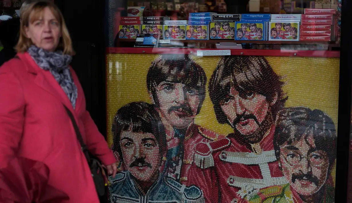 Seorang wanita berjalan melewati gambar The Beatles yang terbuat dari permen  di Liverpool, Inggris, (2/3). Liverpool  tiap tahunnya menadapat 105 juta dollar dari para penggemar The beatles dari seluruh dunia yang hadir ke kota ini. (REUTERS/Phil Noble)