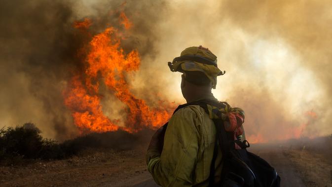 Petugas melihat kebakaran hutan di Cherry Valley, California (1/8/2020). Hampir setiap tahun, California dilanda kebakaran besar-besaran yang menyebabkan polusi udara tinggi. (AP Photo/Ringo H.W. Chiu)
