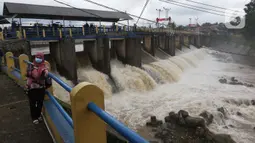 Warga berswafoto di Bendung Katulampa, Bogor, Jawa Barat, Jumat (19/2/2021). Meski sempat mengalami kenaikan debit air pada Jumat (19/2) pagi, namum sekitar pukul 15.00 WIB, debit air di Bendung Katulampa berada di zona hijau dengan ketinggian sekitar 50 cm. (Liputan6.com/Helmi Fithriansyah)