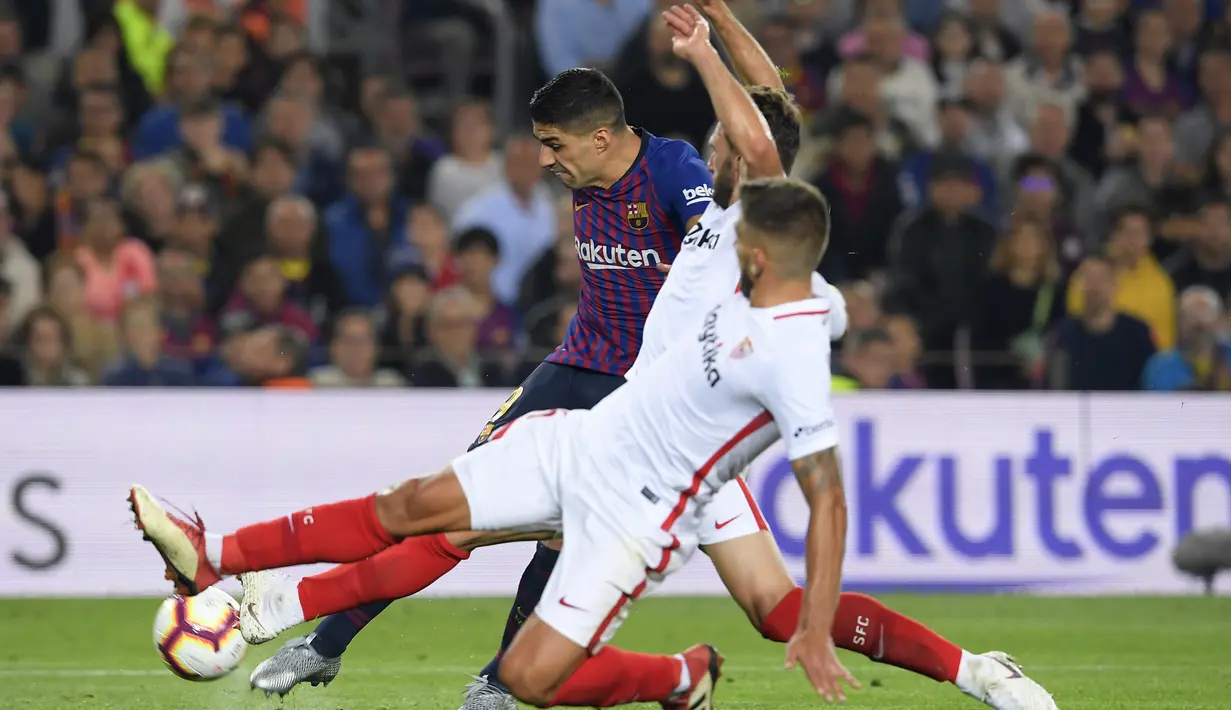 Striker Barcelona, Luis Suarez, berusaha melewati pemain Sevilla pada laga La Liga Spanyol di Stadion Camp Nou, Barcelona, Sabtu (20/10). Barcelona menang 4-2 atas Sevilla. (AFP/Lluis Gene)