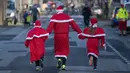 Seorang pria bersama dua anak berkostum Santa Claus ikut dalam kegiatan  Santa Claus Run di Michendorf, Minggu (10/12). Kegiatan amal yang digelar setiap tahun ini diikuti ribuan warga Jerman dan wisatawan mancanegara. (Ralf Hirschberger / dpa / AFP)
