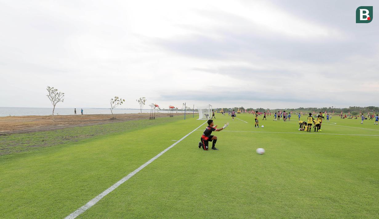 Sejumlah pesepak bola cilik bermain bola di Training Ground Bali United, Gianyar, Senin (28.03/2022). Mereka tampak senang menjajal lapangan latihan Bali United yang berada di pinggir pantai. (Bola.com/ M Iqbal Ichsan)