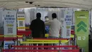 Pekerja medis berbicara kepada orang-orang bahwa tes virus corona pagi hari telah selesai di tempat pengujian darurat di Seoul, Jumat (10/12/2021). Korea Selatan melaporkan lebih dari 7.000 kasus COVID-19 baru untuk ketiga hari berturut-turut pada hari Jumat ini. (AP Photo/Ahn Young-joon)