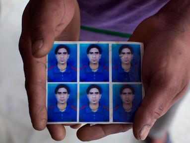 Vijay Kumar menampilkan foto adik laki-lakinya Indrajit Kumar yang jasadnya ditemukan terkubur di barat laut Mosul, India (21/3). Sebanyak 39 warga India yang diculik oleh Kelompok ISIS pada 2014 dikonfirmasi telah tewas. (AP/Ashwini Bhatia)