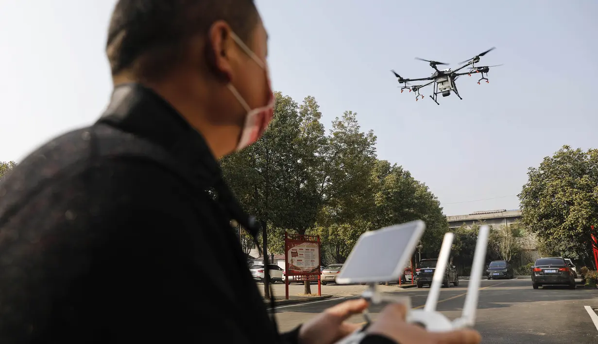 Seorang warga mengoperasikan drone yang membawa cairan desinfektan yang akan disemprotkan ke sebuah desa di Pingdingshan, Provinsi Henan, China (31/1/2020).  Cara ini digunakan untuk mencegah sekaligus mematikan partikel-partikel virus corona yang menyebar di setiap sudut daerah. (AFP Photo/Str)