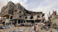 Anak-anak berdiri di luar gedung keluarga Sabah yang terkena serangan udara Israel di Deir el-Balah, Jalur Gaza tengah pada 8 April 2025. (Eyad BABA/AFP)