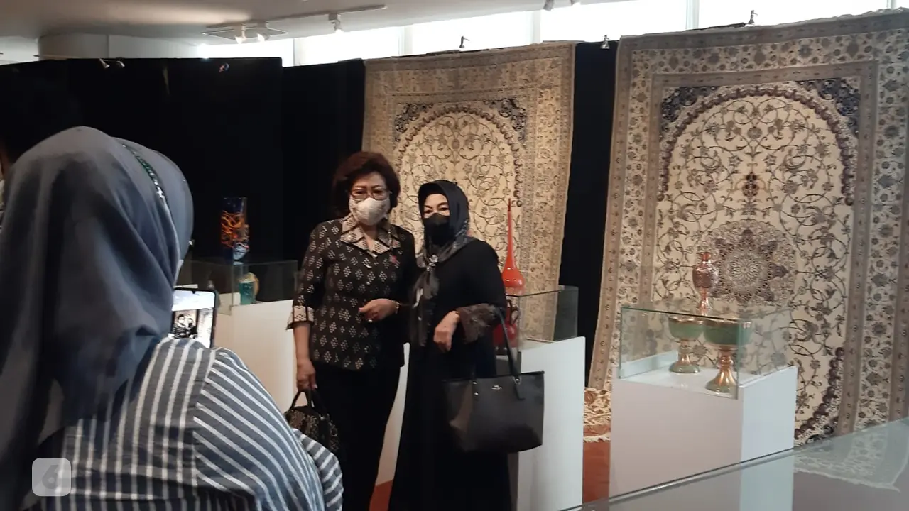 Pengunjung mengambil foto dengan latar karpet Iran di Perpusnas.